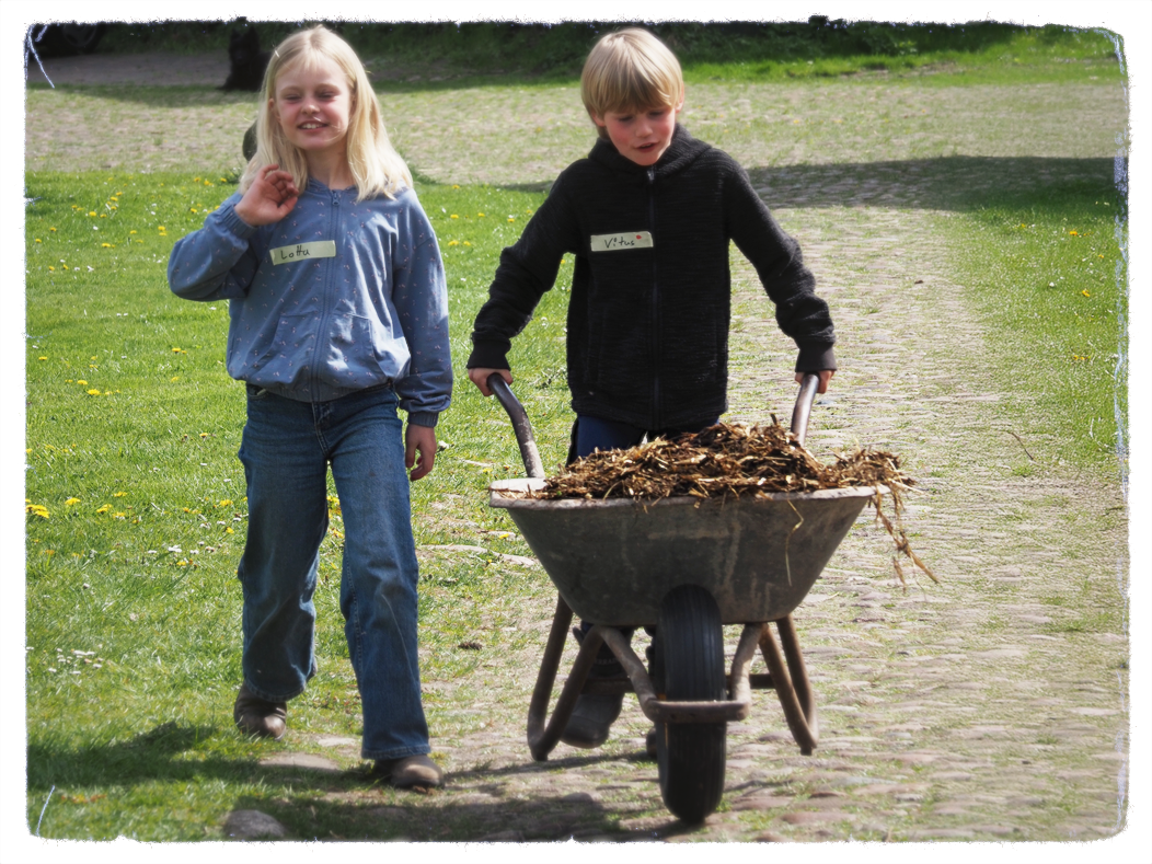 Kinder beim Schieben einer Mistkarre